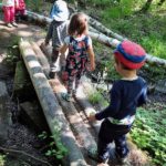 Kinder balancieren über Holzstämme über den Fluss